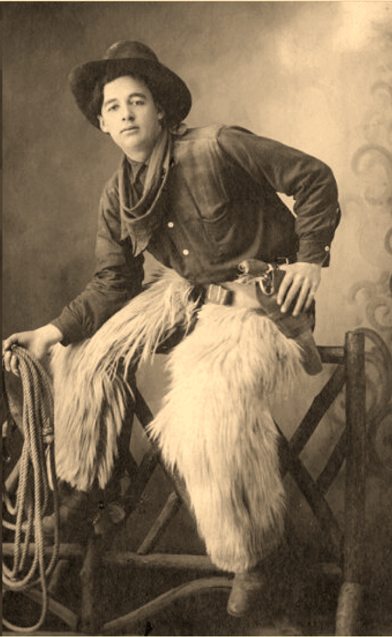 Archival-style portrait evoking Guy Weadick in full Western dress, chaps and coiled rope, seated on a rail